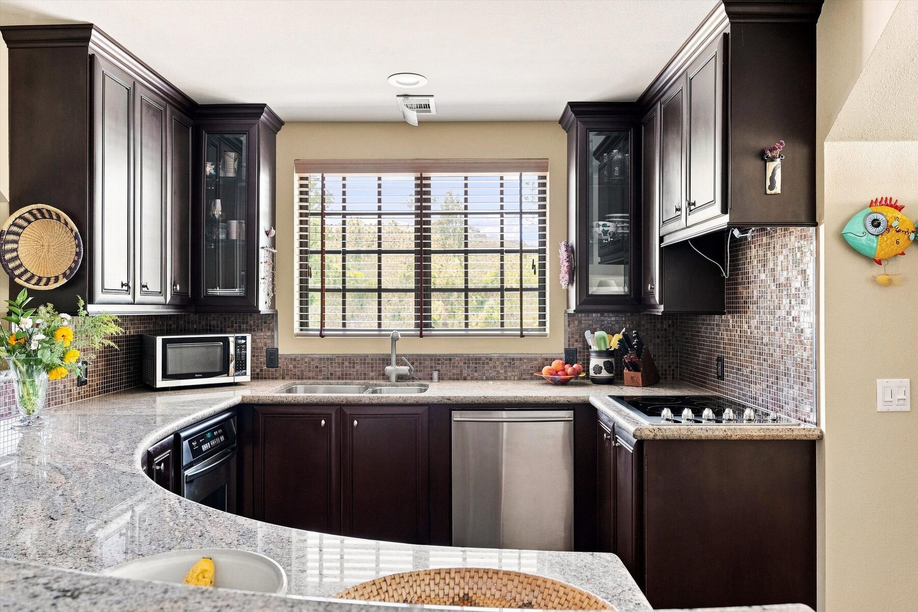 16330 Askin Drive — kitchen with dark cabinetry, mosaic backsplash, and wooded view