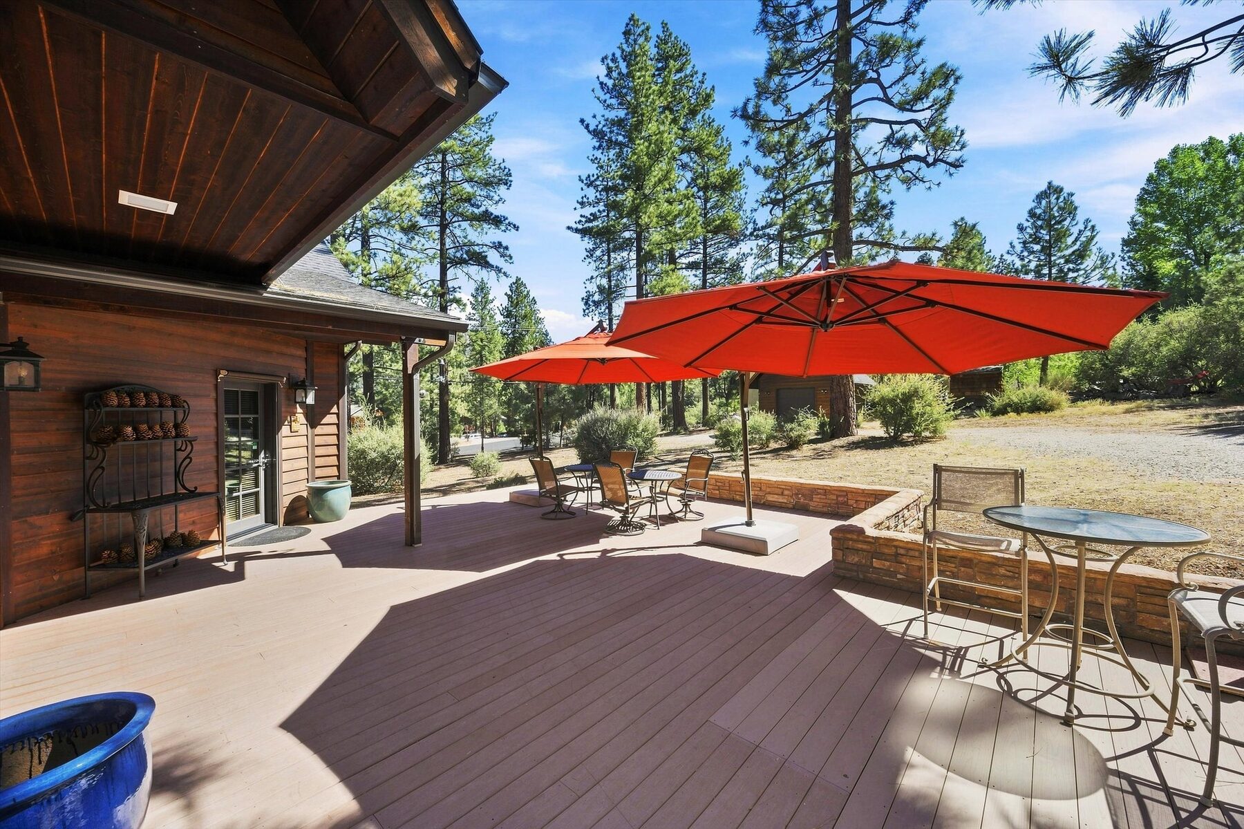 16330 Askin Drive — outdoor patio with dining tables, red umbrellas, and pine trees