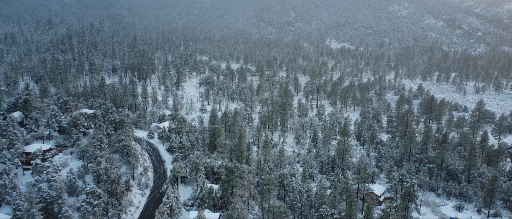 Aerial view of snow-covered mountain homes and pine forest in the Frazier Mountain communities
