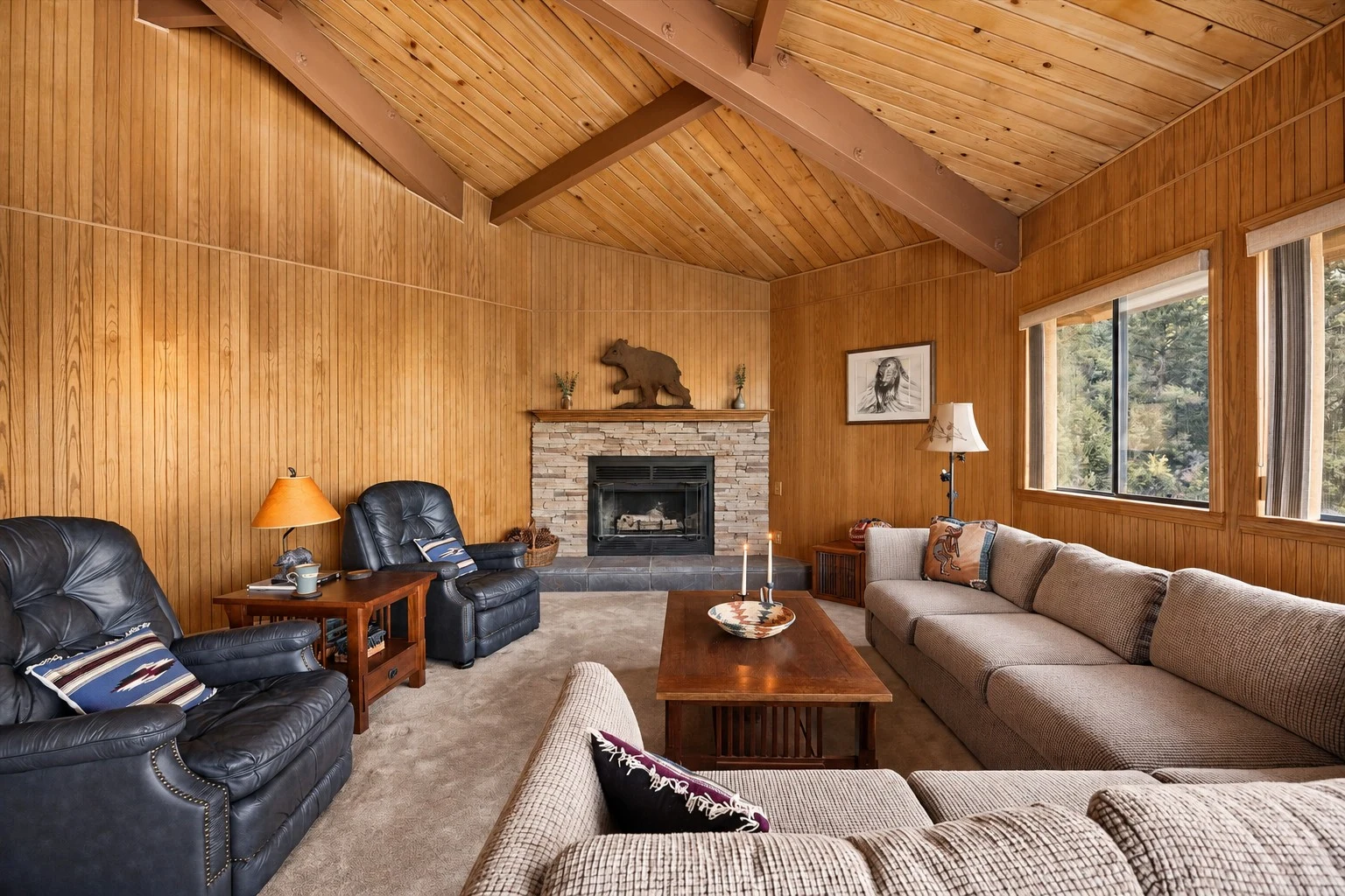 2104 Ironwood Drive — Wood-paneled living room with vaulted ceiling and stone fireplace