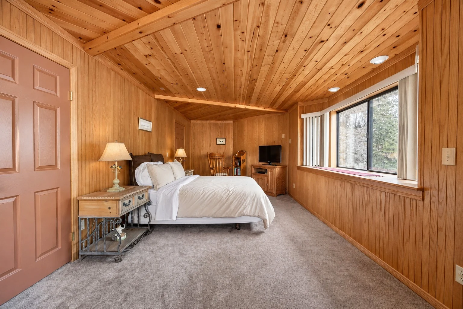 2104 Ironwood Drive — Primary bedroom with wood-paneled walls and large windows